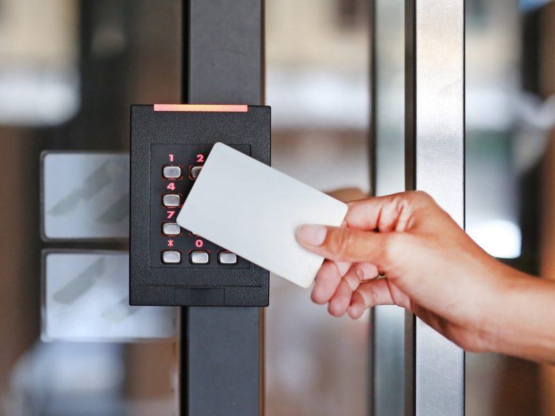 Door access control - young woman holding a key card to lock and unlock door.
